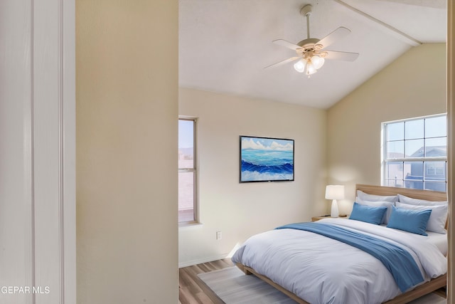 bedroom featuring vaulted ceiling, ceiling fan, light hardwood / wood-style flooring, and multiple windows