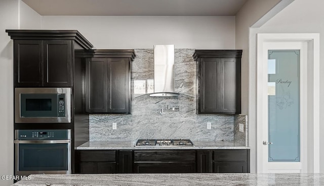 kitchen with backsplash, light stone countertops, wall chimney range hood, and stainless steel appliances