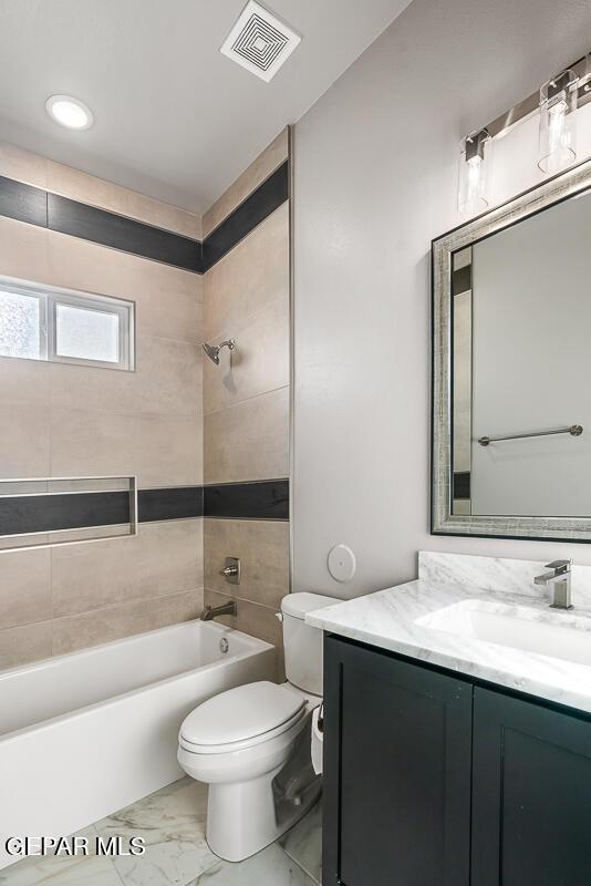 full bathroom featuring toilet, tiled shower / bath combo, and vanity