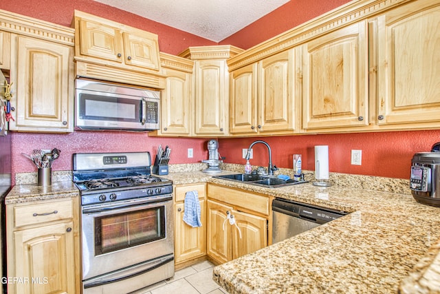 kitchen featuring light stone countertops, light brown cabinets, stainless steel appliances, sink, and light tile patterned floors