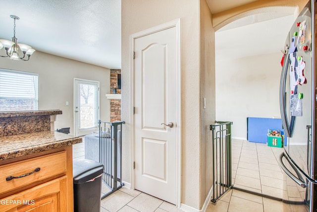 kitchen with decorative light fixtures, stainless steel fridge, a notable chandelier, and light tile patterned flooring