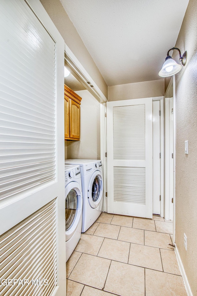 clothes washing area with light tile patterned floors, cabinets, and washer and dryer