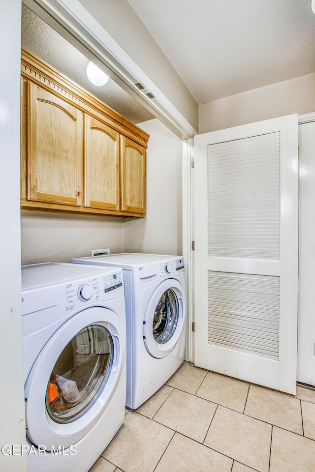 laundry area featuring light tile patterned floors, cabinets, and washer and clothes dryer