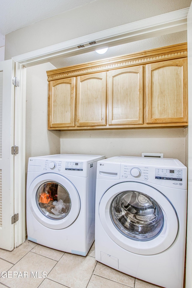 clothes washing area featuring cabinets, light tile patterned floors, and separate washer and dryer