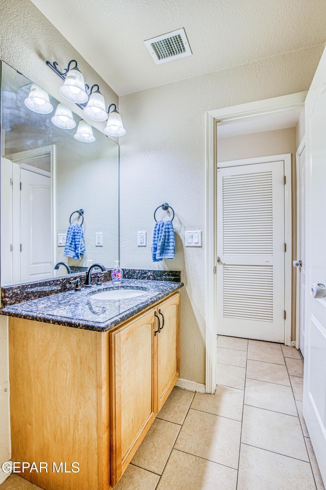 bathroom with a textured ceiling, tile patterned floors, and vanity