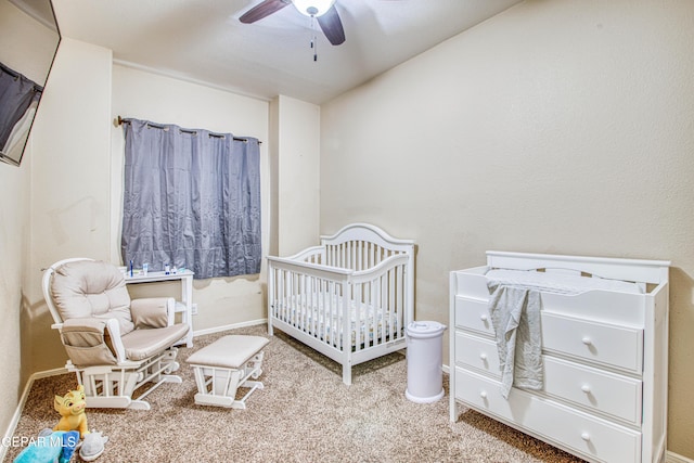 carpeted bedroom featuring ceiling fan and a crib