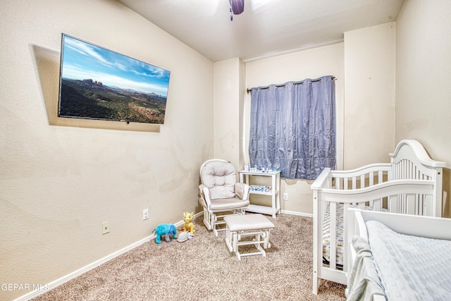 carpeted bedroom featuring a crib and ceiling fan