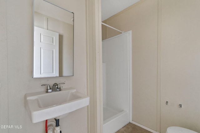 bathroom with toilet, walk in shower, and sink