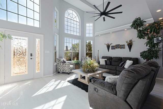 living room with ceiling fan, a wealth of natural light, and a towering ceiling