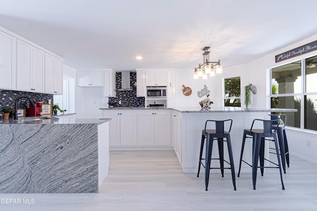 kitchen featuring hanging light fixtures, sink, stainless steel appliances, and white cabinetry