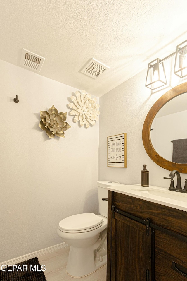 bathroom featuring a textured ceiling, toilet, and vanity