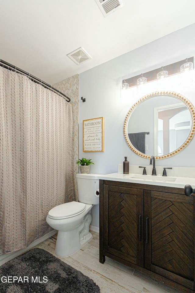 bathroom featuring toilet, vanity, and curtained shower