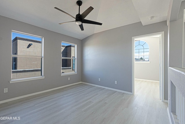 empty room with ceiling fan, lofted ceiling, and light hardwood / wood-style flooring