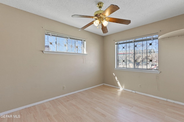 empty room with a textured ceiling, ceiling fan, light hardwood / wood-style floors, and plenty of natural light