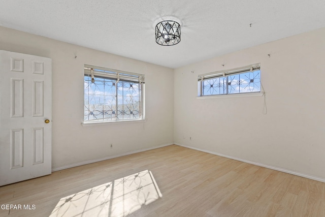 empty room with a textured ceiling and light wood-type flooring