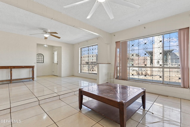 unfurnished living room with ceiling fan, light tile patterned flooring, and a textured ceiling