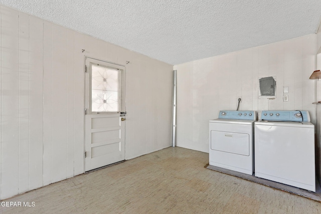 laundry area with washer and dryer, a textured ceiling, and wood walls