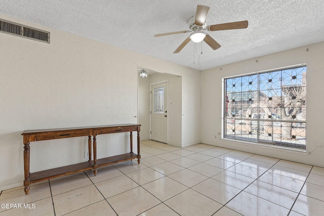 tiled spare room featuring a textured ceiling and ceiling fan