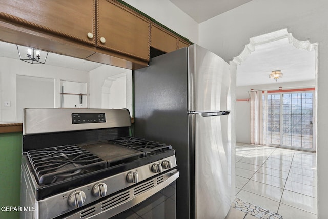 kitchen with light tile patterned floors, stainless steel appliances, and an inviting chandelier