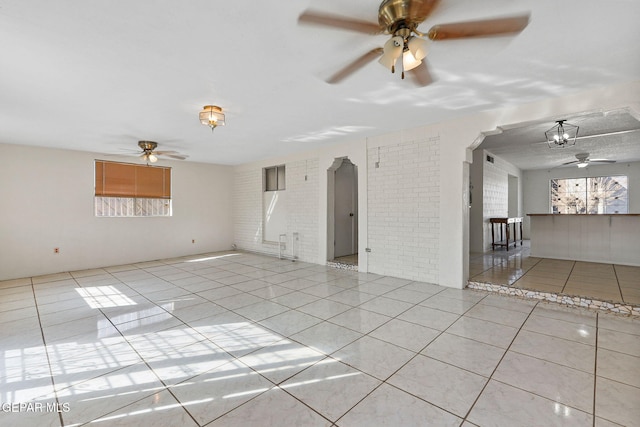 unfurnished room with light tile patterned floors and brick wall