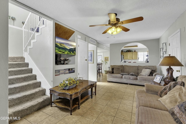 living room with a textured ceiling, ceiling fan, and light tile patterned floors