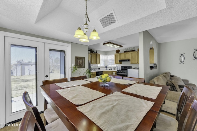 dining space featuring french doors, sink, a chandelier, and a textured ceiling