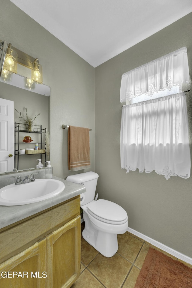 bathroom with toilet, vanity, and tile patterned floors