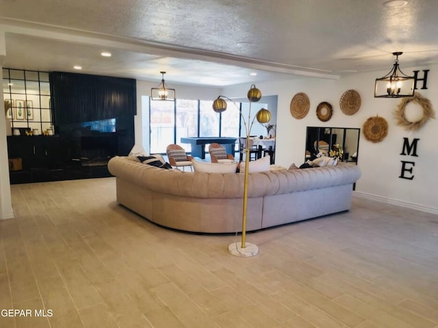 living room featuring light hardwood / wood-style floors, a textured ceiling, beam ceiling, and an inviting chandelier