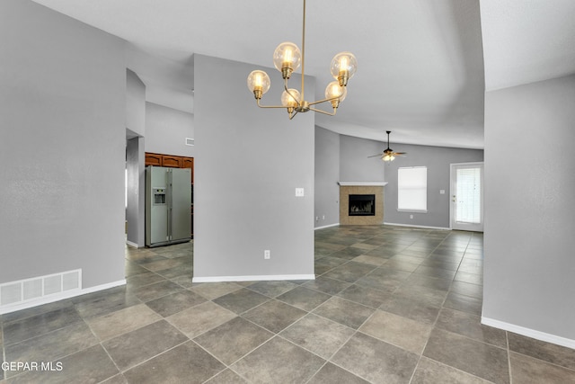 unfurnished living room with ceiling fan with notable chandelier, a tiled fireplace, and high vaulted ceiling