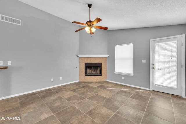 unfurnished living room with ceiling fan, a textured ceiling, lofted ceiling, and a fireplace