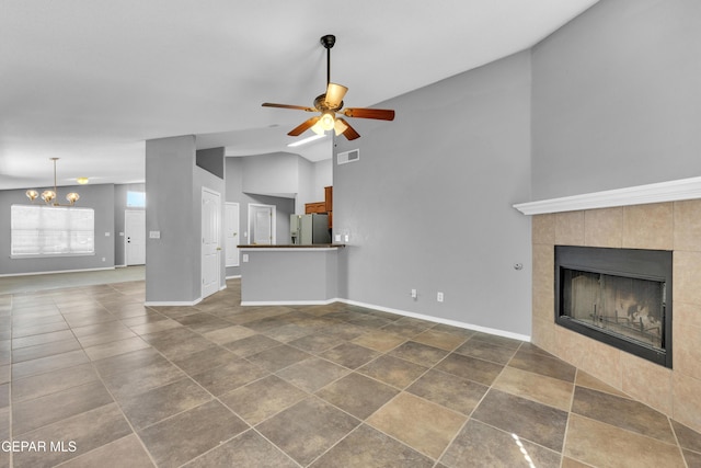 unfurnished living room with lofted ceiling, a fireplace, and ceiling fan with notable chandelier