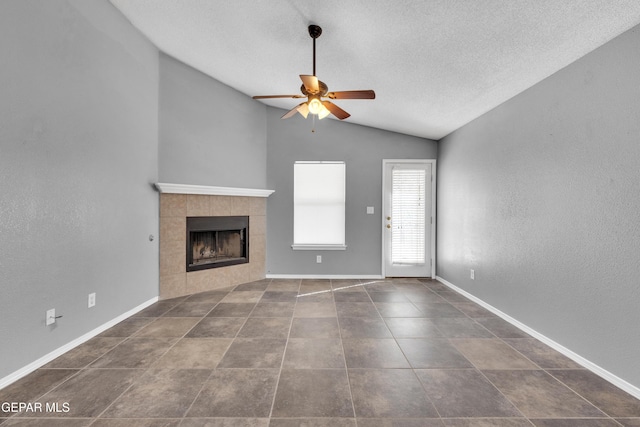 unfurnished living room featuring ceiling fan, a textured ceiling, lofted ceiling, and a tiled fireplace