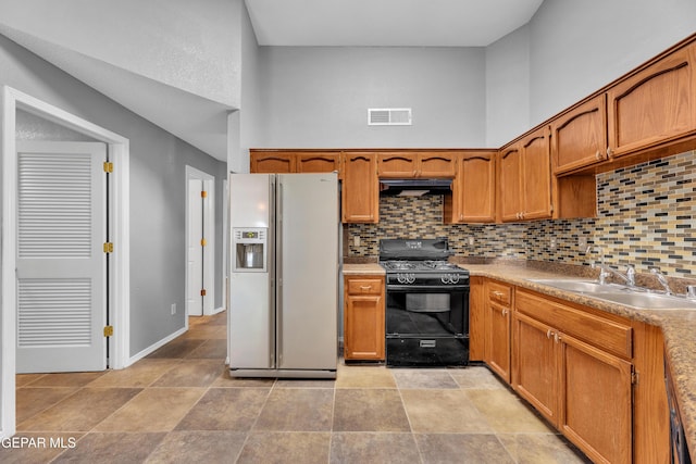 kitchen featuring sink, white refrigerator with ice dispenser, black range with gas cooktop, and tasteful backsplash