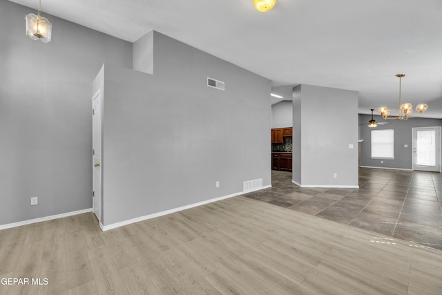 unfurnished living room with ceiling fan with notable chandelier and hardwood / wood-style floors