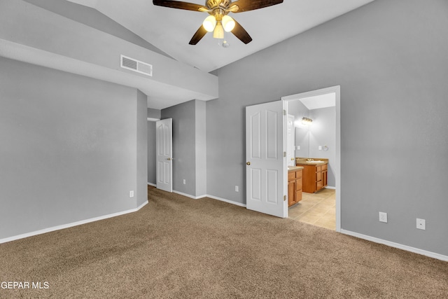 interior space featuring ceiling fan, lofted ceiling, light colored carpet, and ensuite bath