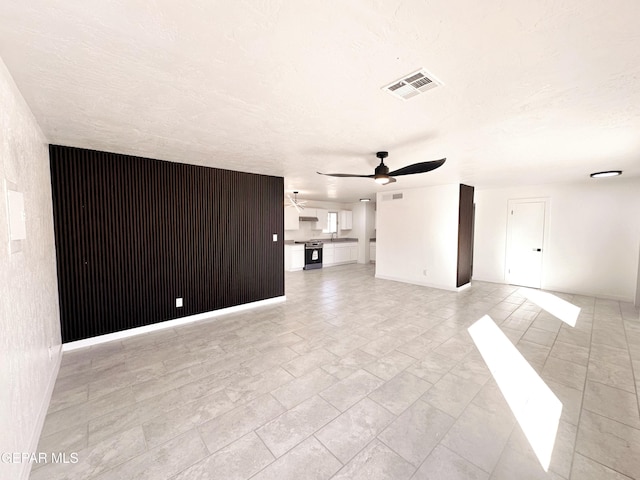 unfurnished living room with ceiling fan and a textured ceiling