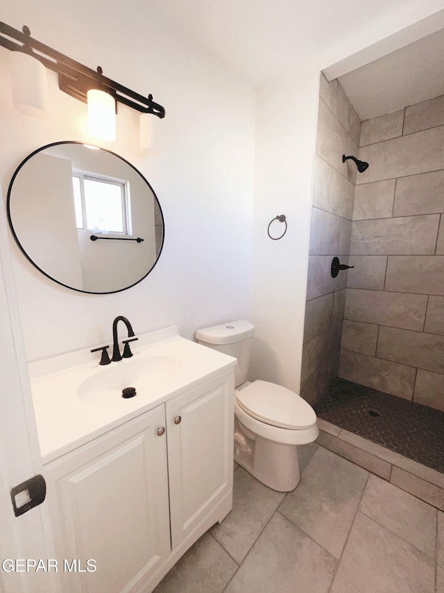 bathroom featuring vanity, toilet, and tiled shower