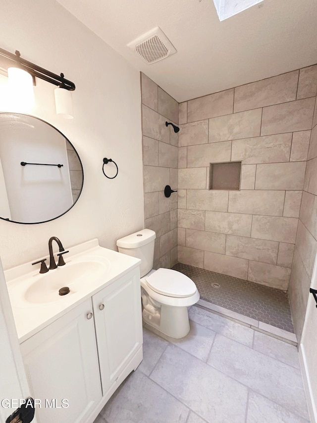 bathroom with vanity, toilet, and tiled shower