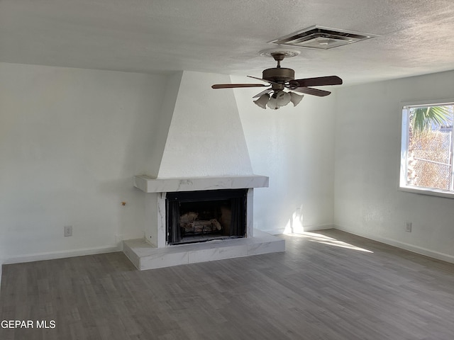 unfurnished living room with a fireplace, wood-type flooring, a textured ceiling, and ceiling fan