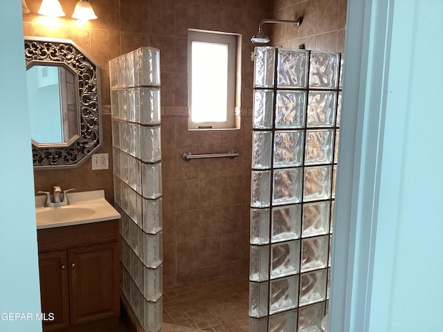 bathroom with a tile shower and vanity