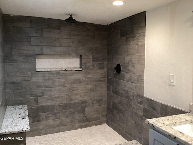 bathroom with vanity, tile walls, and a tile shower