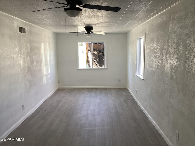 unfurnished room featuring ceiling fan, a wealth of natural light, and dark hardwood / wood-style floors