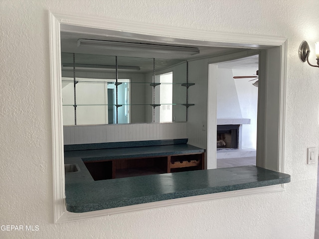 interior details with ceiling fan and a large fireplace