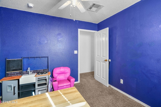 playroom with carpet floors, ceiling fan, sink, and a textured ceiling