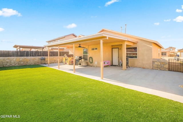 back of property with ceiling fan, a yard, and a patio