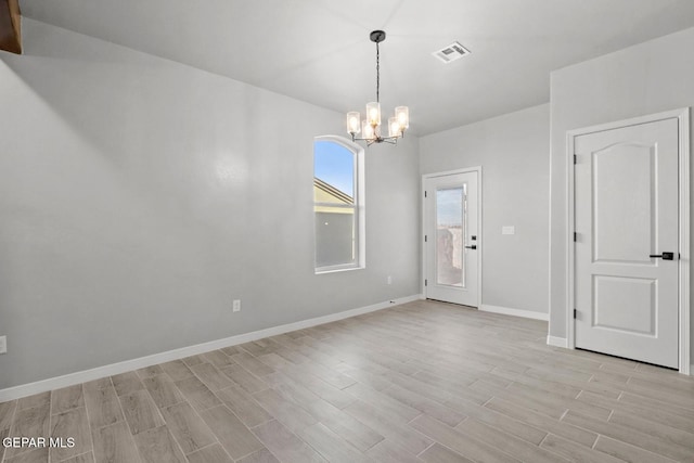 unfurnished room featuring a notable chandelier and light hardwood / wood-style flooring