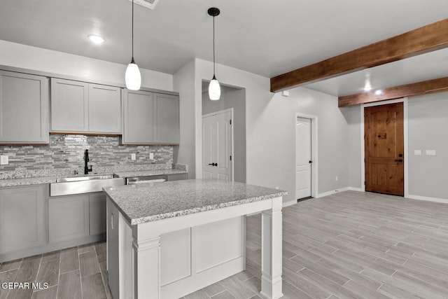 kitchen featuring light stone countertops, sink, gray cabinetry, and pendant lighting