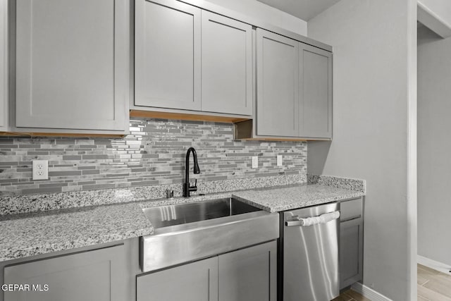 kitchen with light stone countertops, dishwasher, and gray cabinets