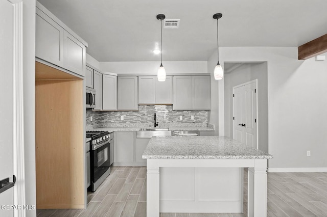 kitchen with sink, appliances with stainless steel finishes, pendant lighting, and gray cabinets