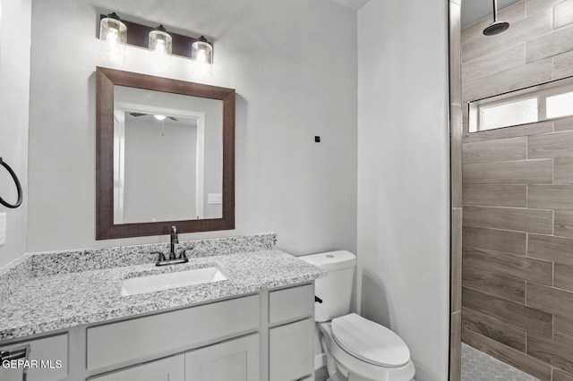 bathroom featuring toilet, vanity, and tiled shower